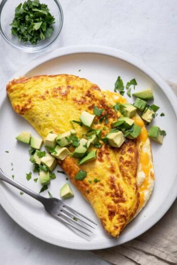 Large plate of souffle omelette topped with avocados and parsley