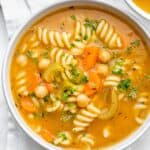 Large bowl of vegetarian chickpea noodle soup on white background
