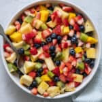 Overhead shot of large serving bowl of fresh fruit salad with a variety of chopped fruit.