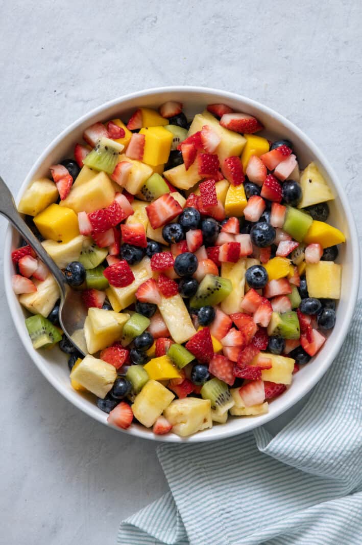 Overhead shot of large serving bowl of fresh fruit salad with a variety of chopped fruit.