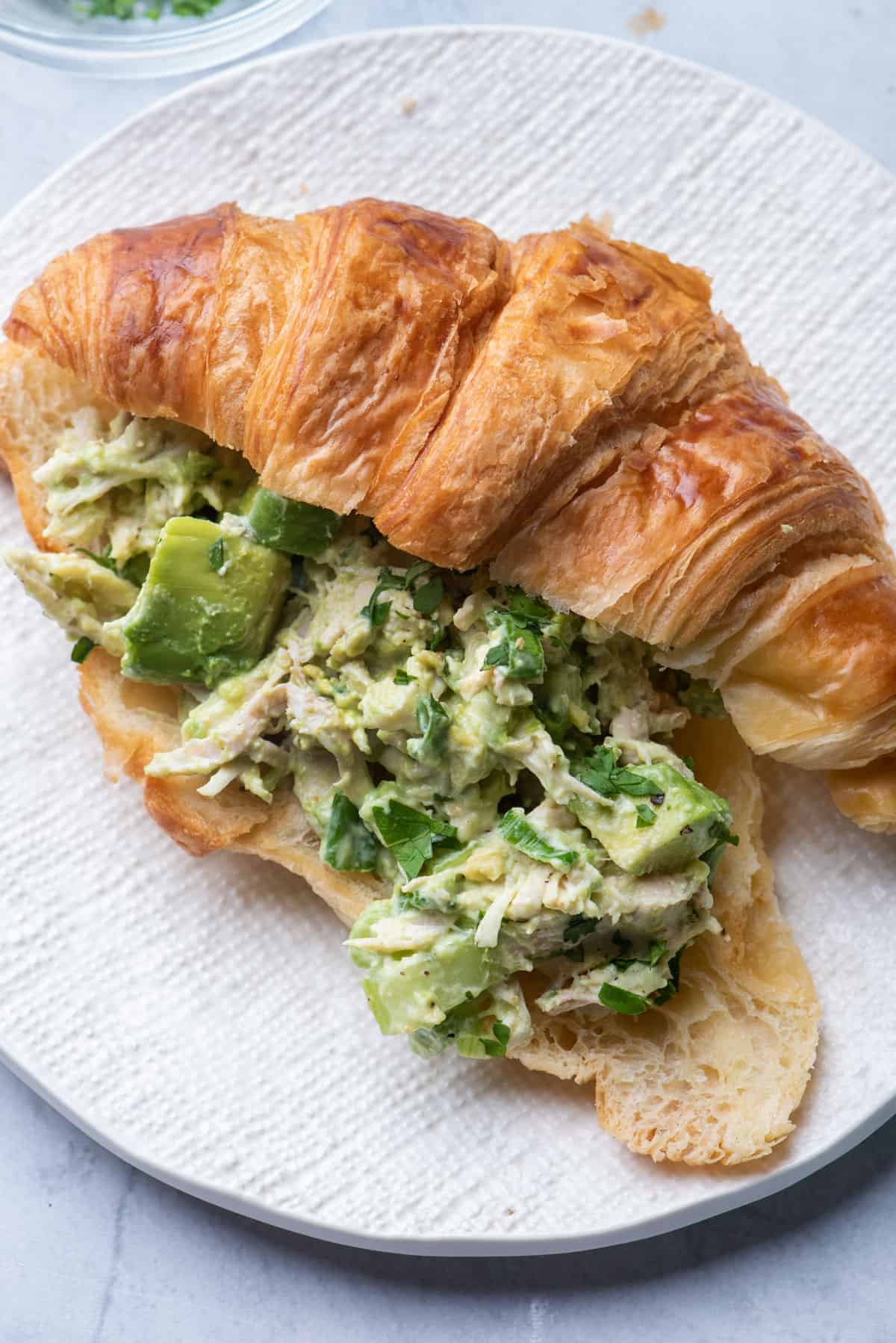 Avocado chicken salad served in a croissant for an easy lunch sandwiche