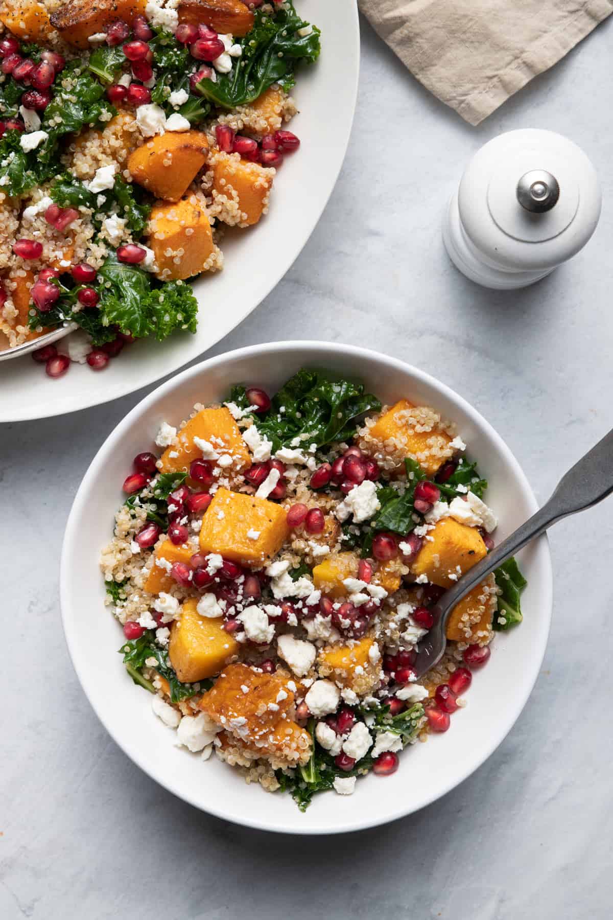 One small bowl of butternut squash quinoa salad served with larger bowl next to it