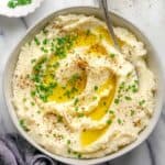 Large bowl of cauliflower mashed potatoes topped with melted butter and chives
