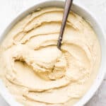 Homemade cashew butter in a small bowl with a spoon dipped in.