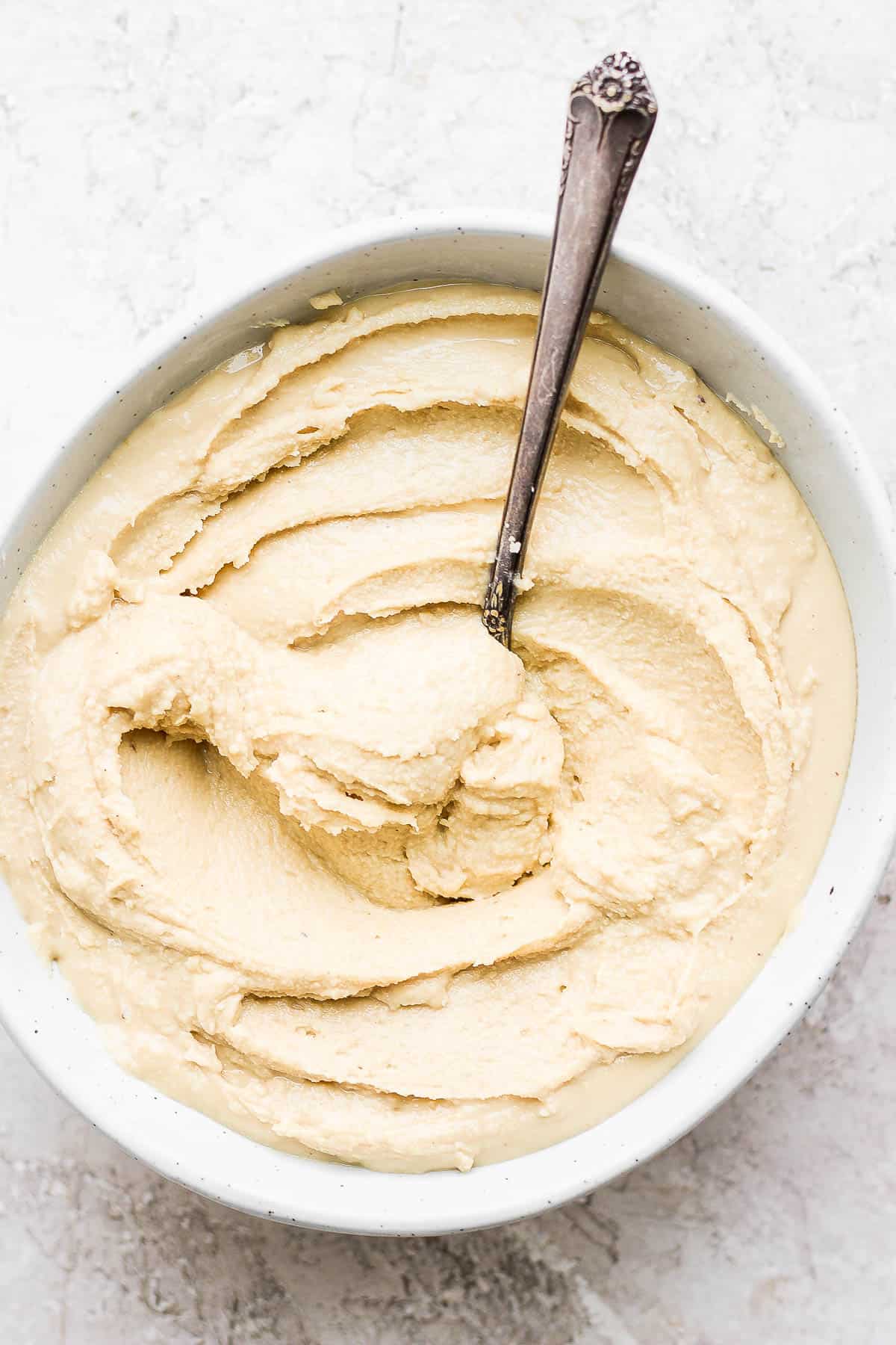 Homemade cashew butter in a small bowl with a spoon dipped in.