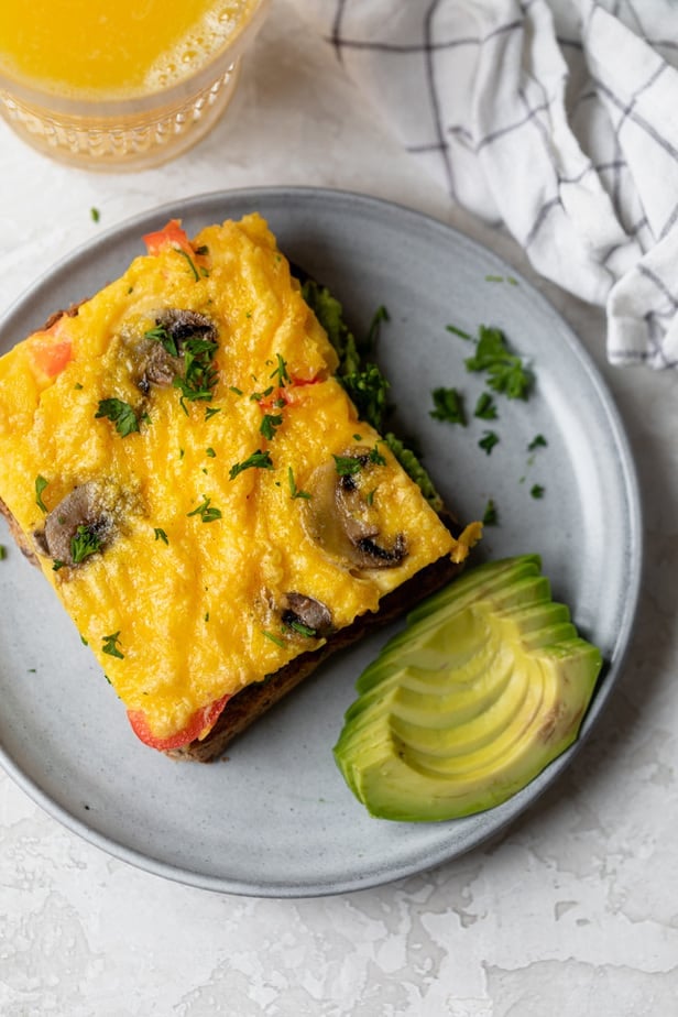 Sheet pan eggs served on toast with sliced avocado