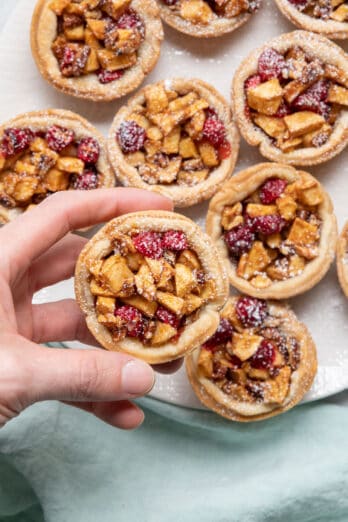 Hand holding cranberry apple mini pies.