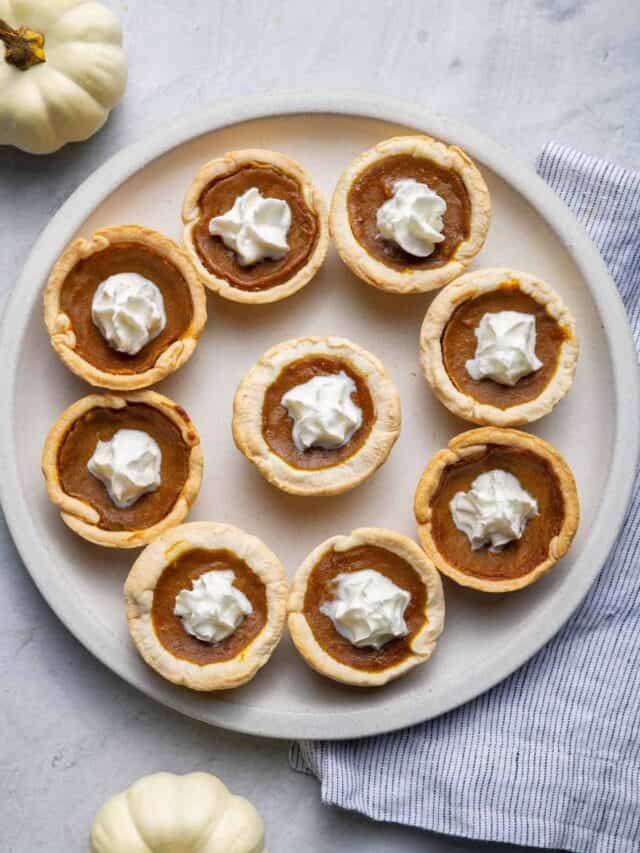 Mini pumpkin pies on a large plate with whipped cream in the middle