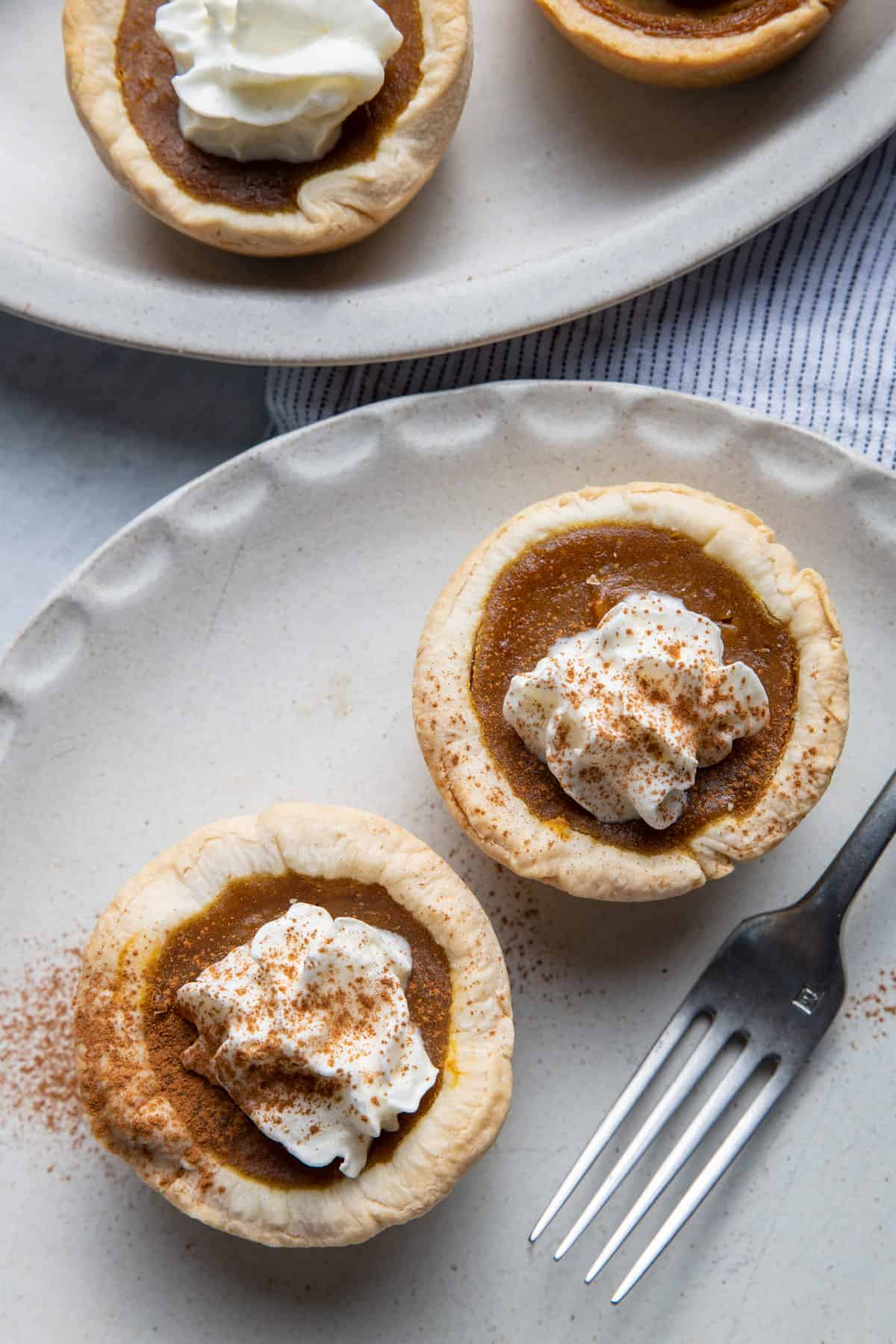 Two mini pumpkin pies on a small plate with the fork