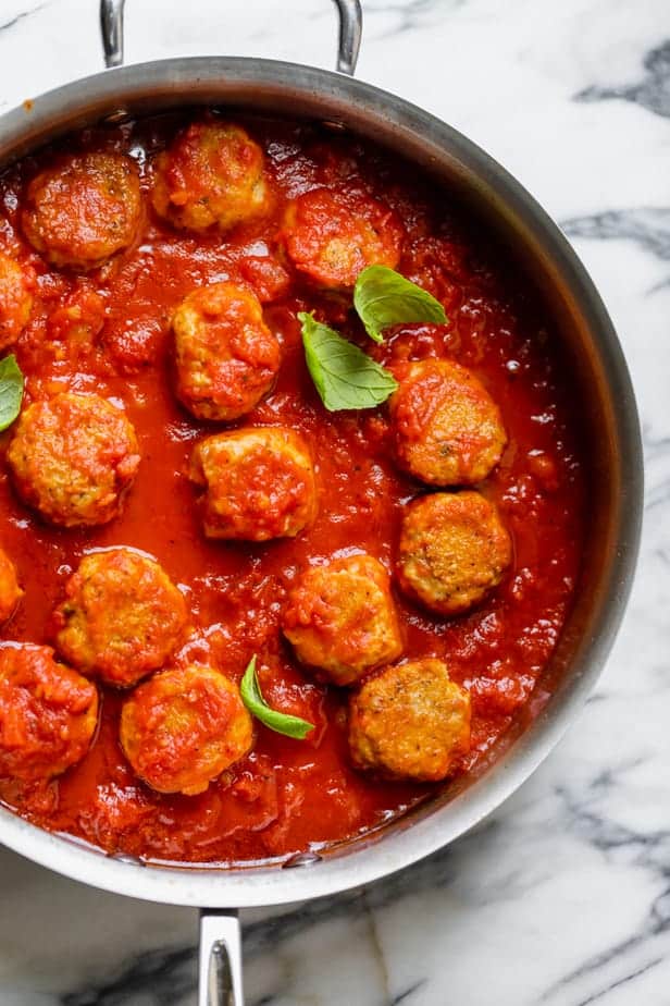 Chicken meatballs simmering in marinara sauce in a large saucepan