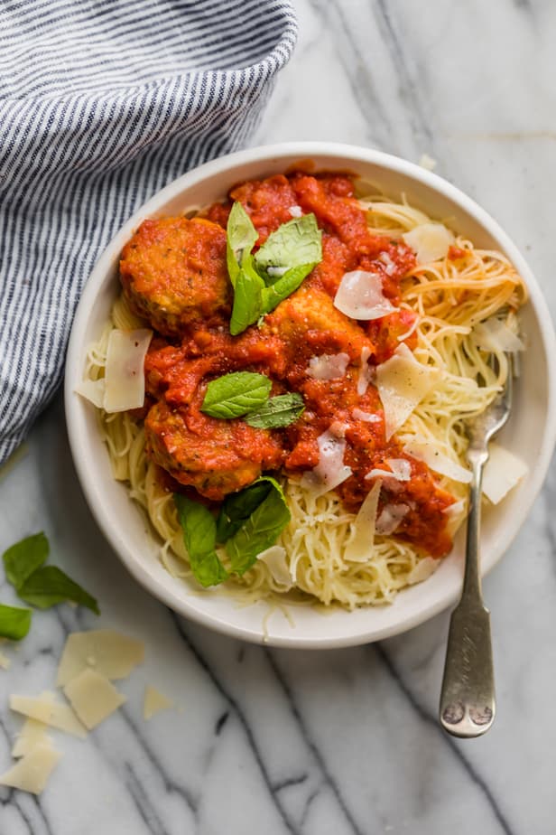 Chicken meatball recipe in a ball with angle hair pasta and fresh basil