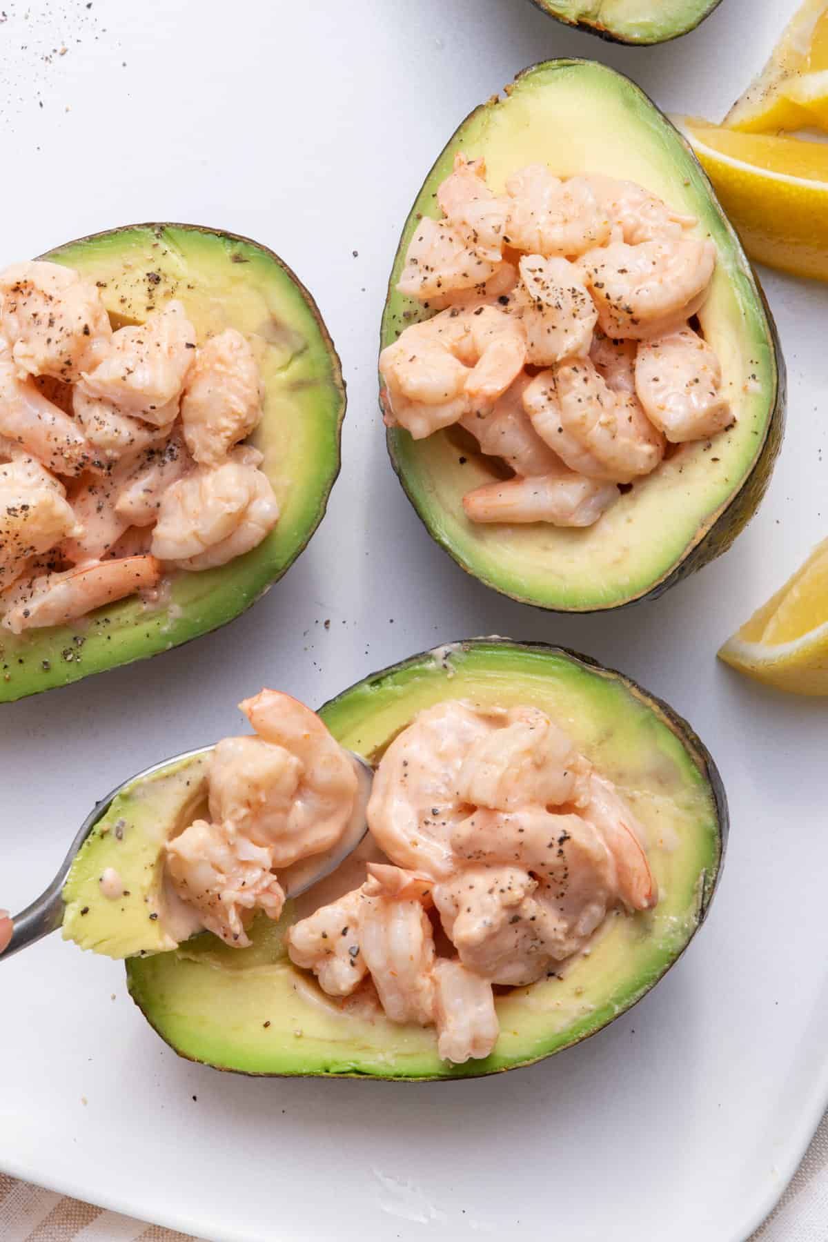 Spoon scooping out bite of shrimp cocktail with avocado
