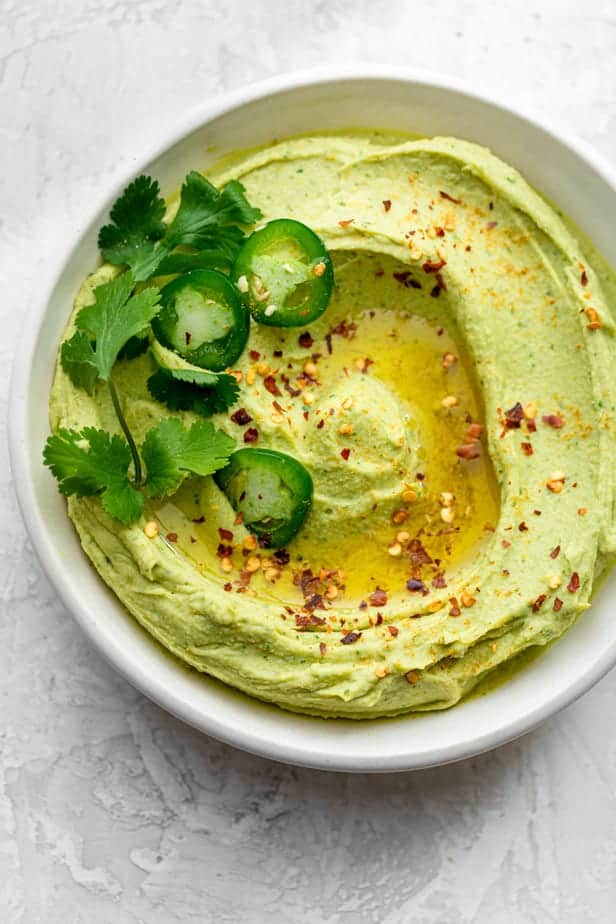 Top down shot of avocado hummus dip in a white bowl