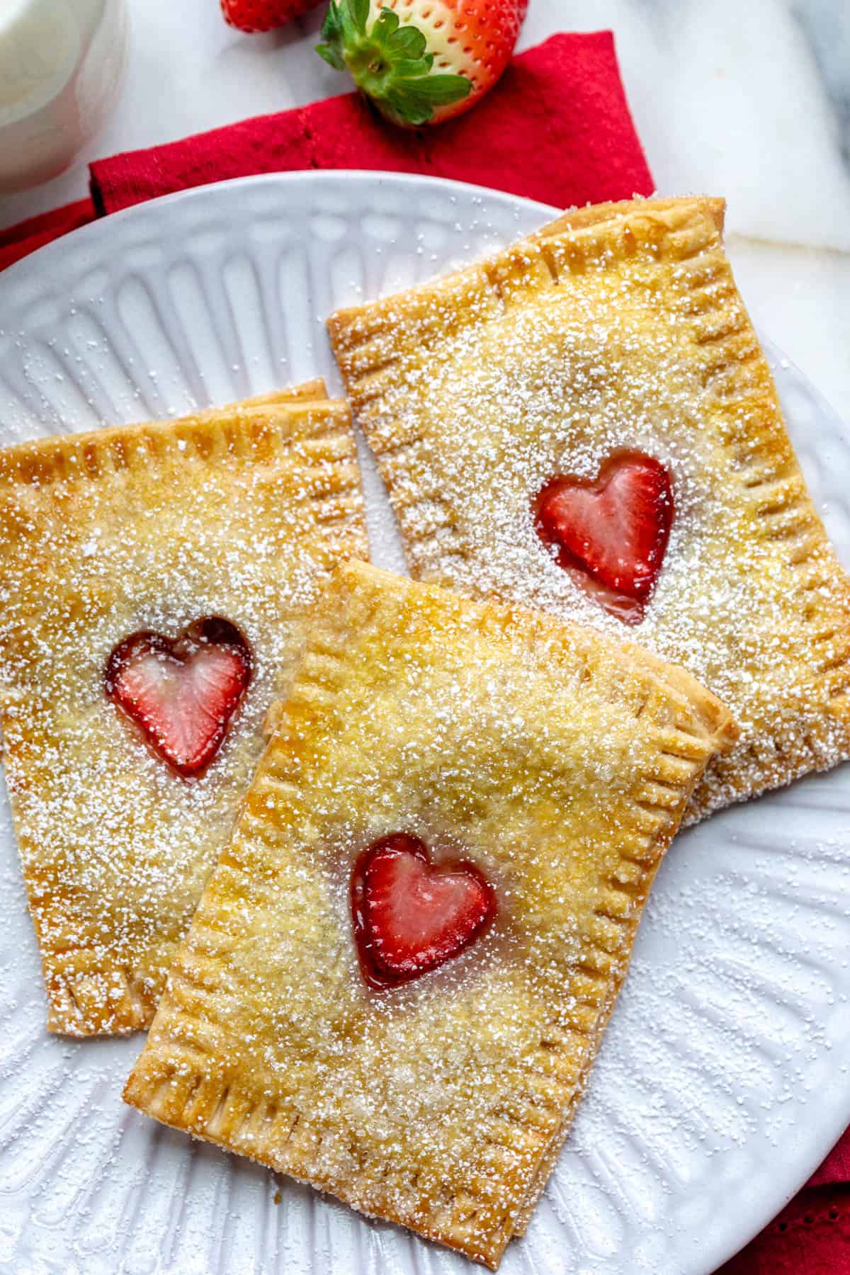 Close up of 3 homemade pop tarts with hearts cut out sprinkled with powdered sugar