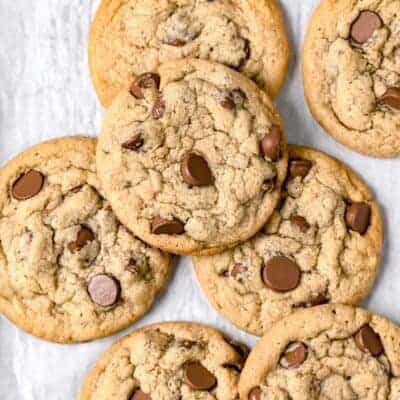 Close up shot of many tahini chocolate chip cookies on a parchment paper background