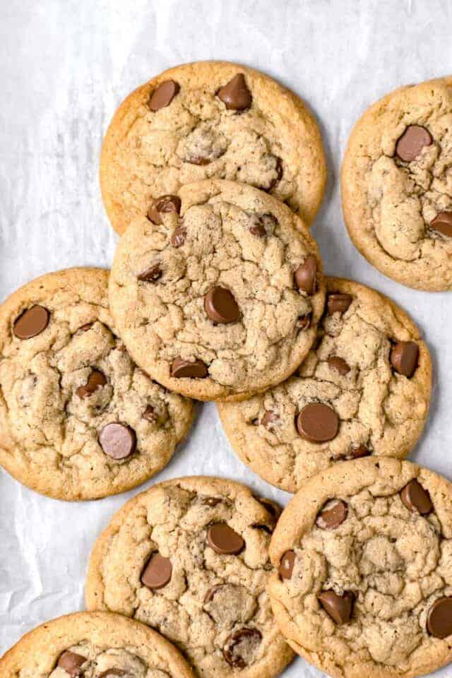 Close up shot of many tahini chocolate chip cookies on a parchment paper background