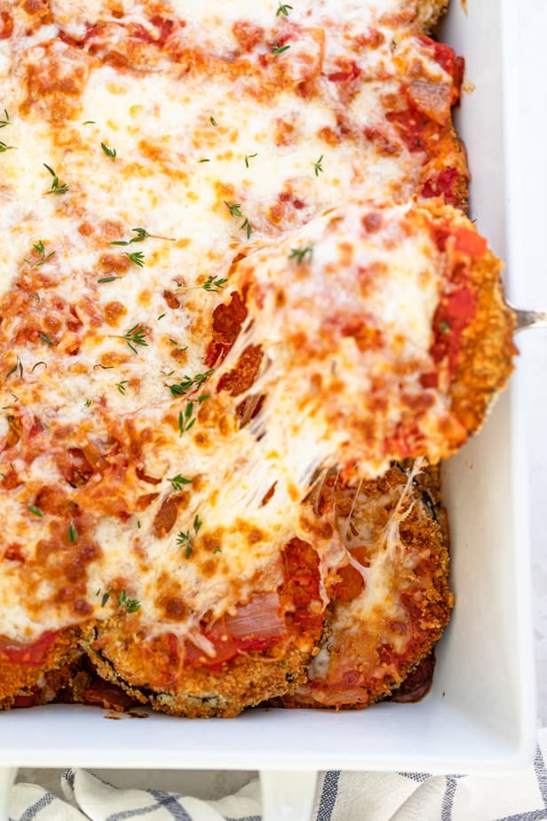 Serving a slice of the eggplant parmesan with the cheese pull showing