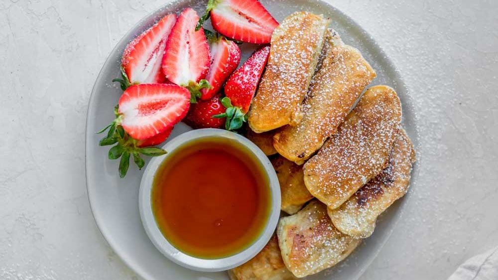 Banana Pancake Dippers on a white plate with strawberries