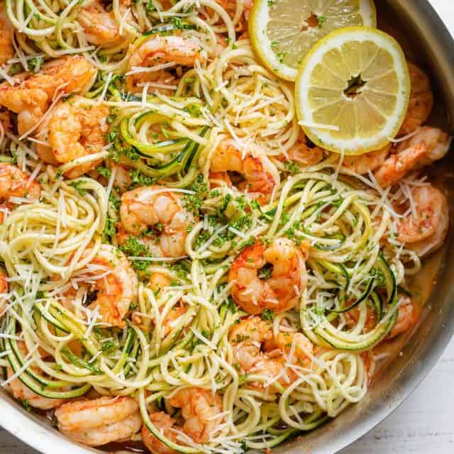 Healthy shrimp scampi made with half pasta and half zucchini topped with lemon slices