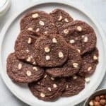 A plate of chocolate hazelnut cookies with a glass of milk