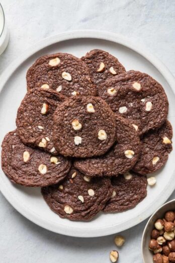 A plate of chocolate hazelnut cookies with a glass of milk