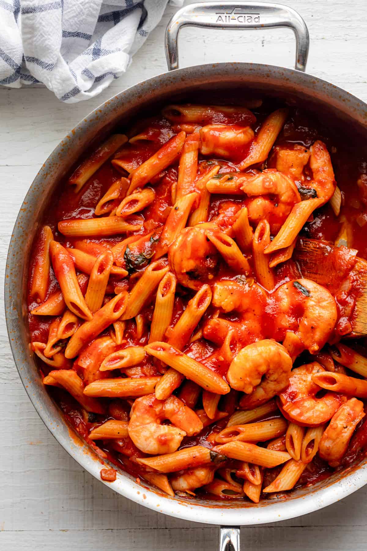 Large stainless steel pan of pasta mixed with shrimp to show everything tossed together