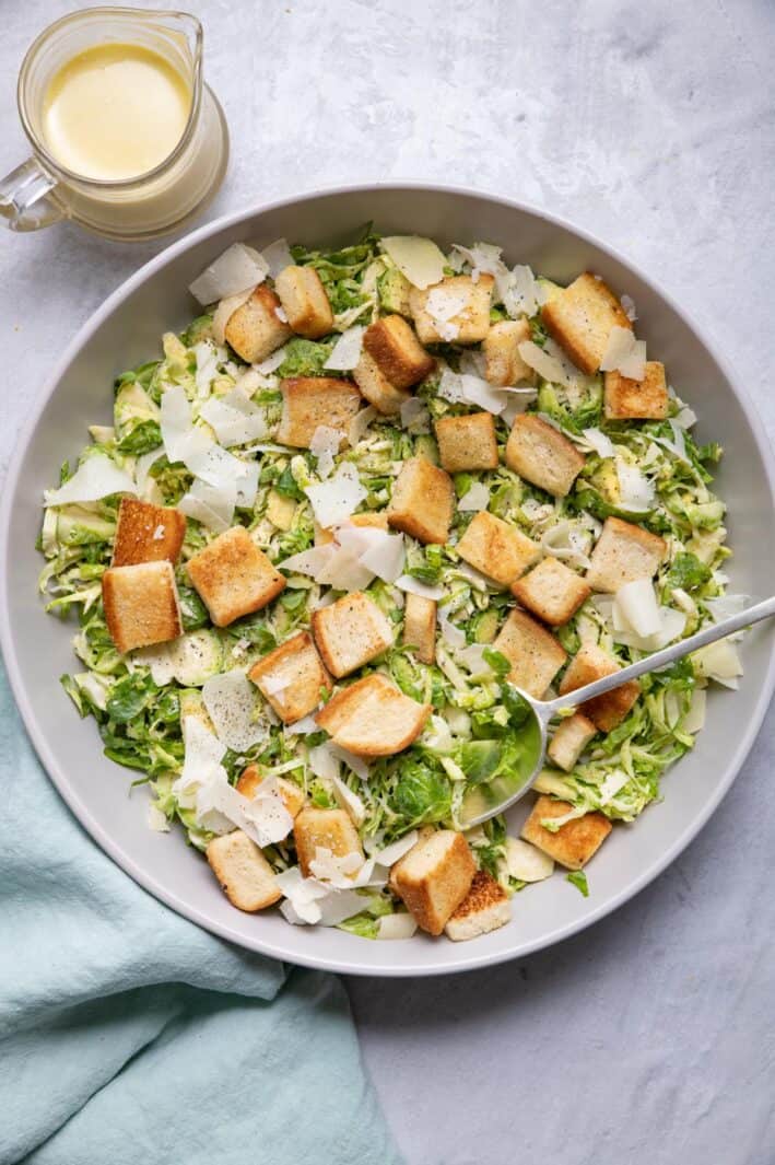 Large bowl of brussel sprout salad with caesar dressing and croutons