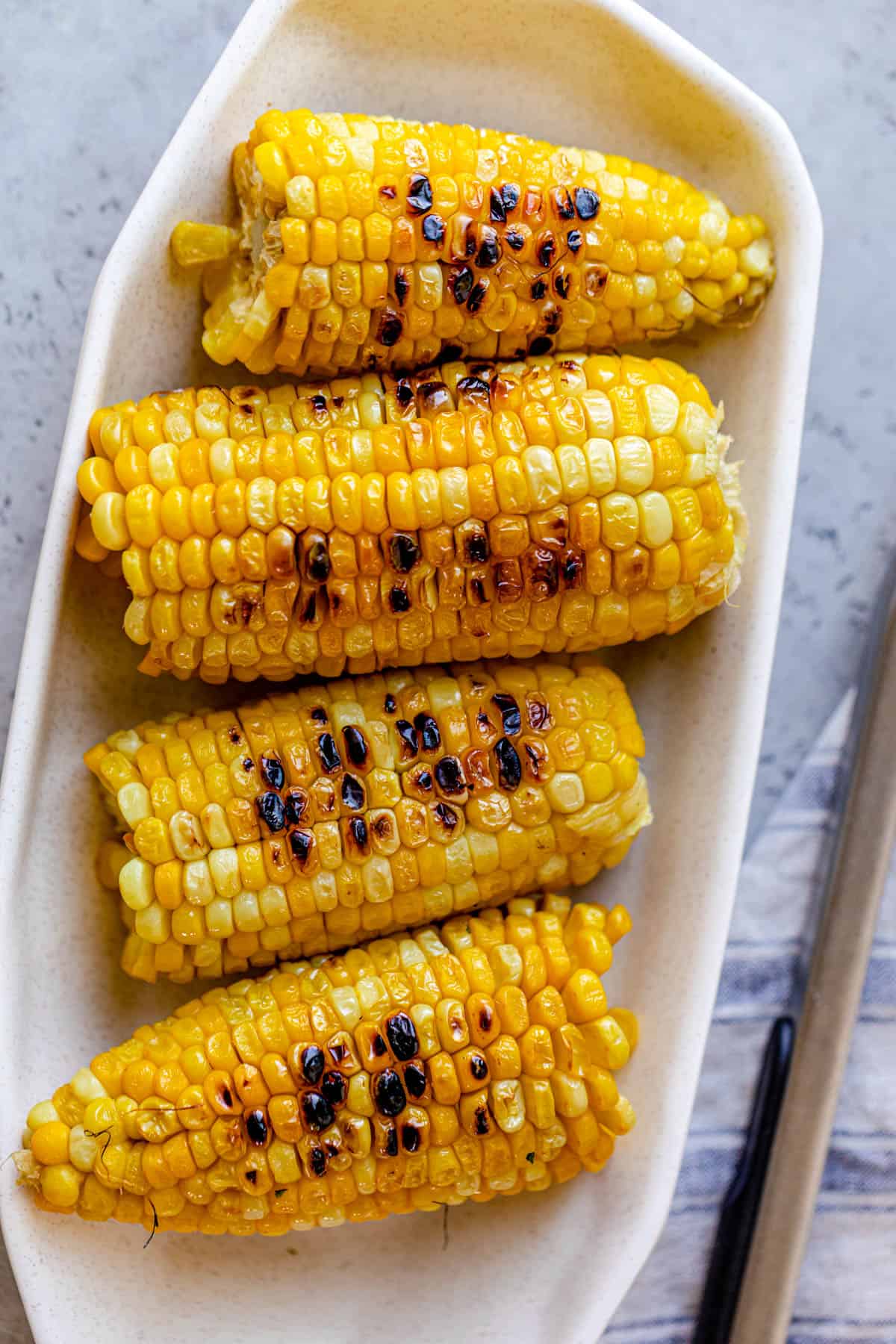 White long bowl with four halves or corn ears with grill marks on them