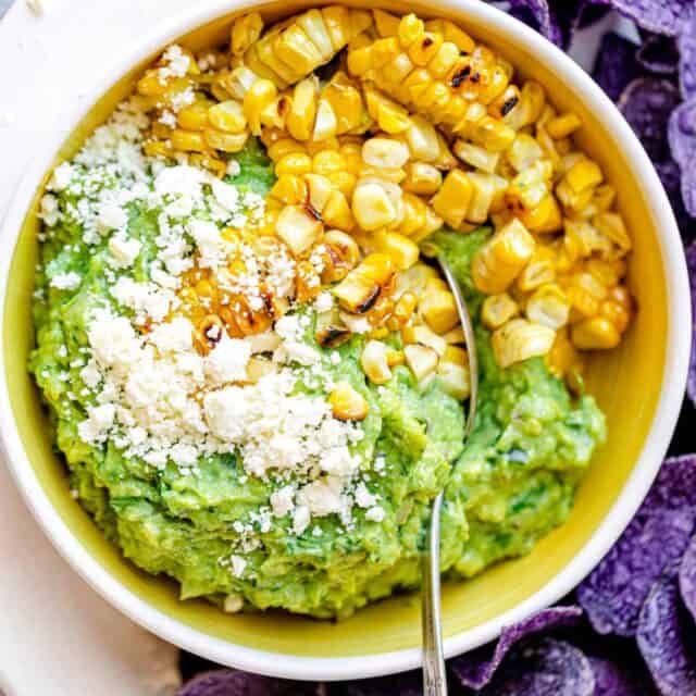 Finished bowl of guacamole up-close focusing on the grilled corn and the cheese