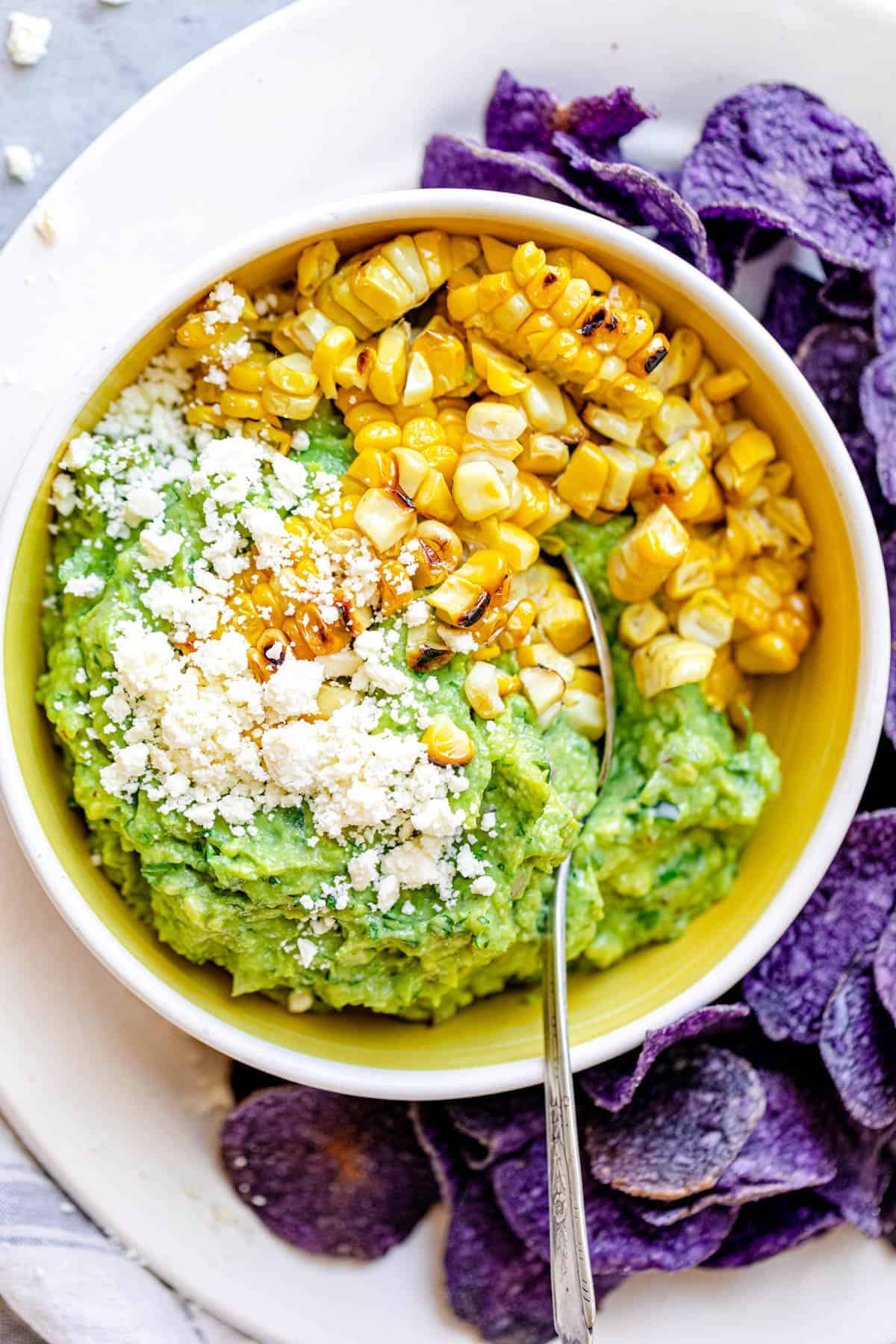 Finished bowl of guacamole up-close focusing on the grilled corn and the cheese