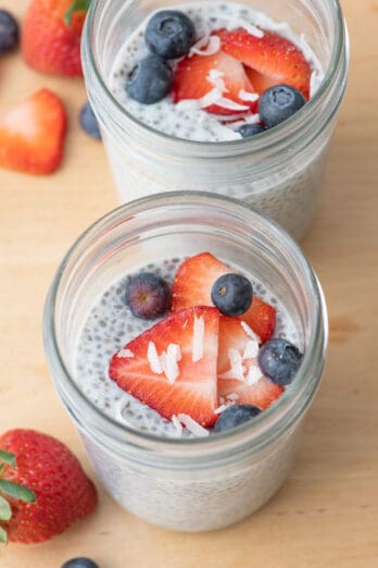 2 jars of chia pudding with fruit on top looking into jar.