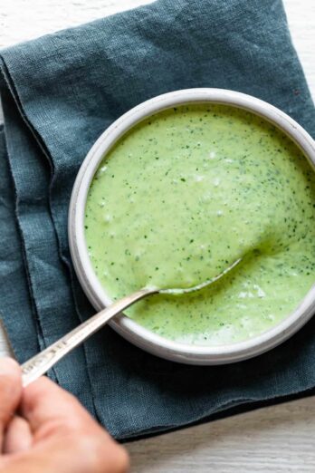 Cilantro yogurt sauce in a small bowl with spoon for serving