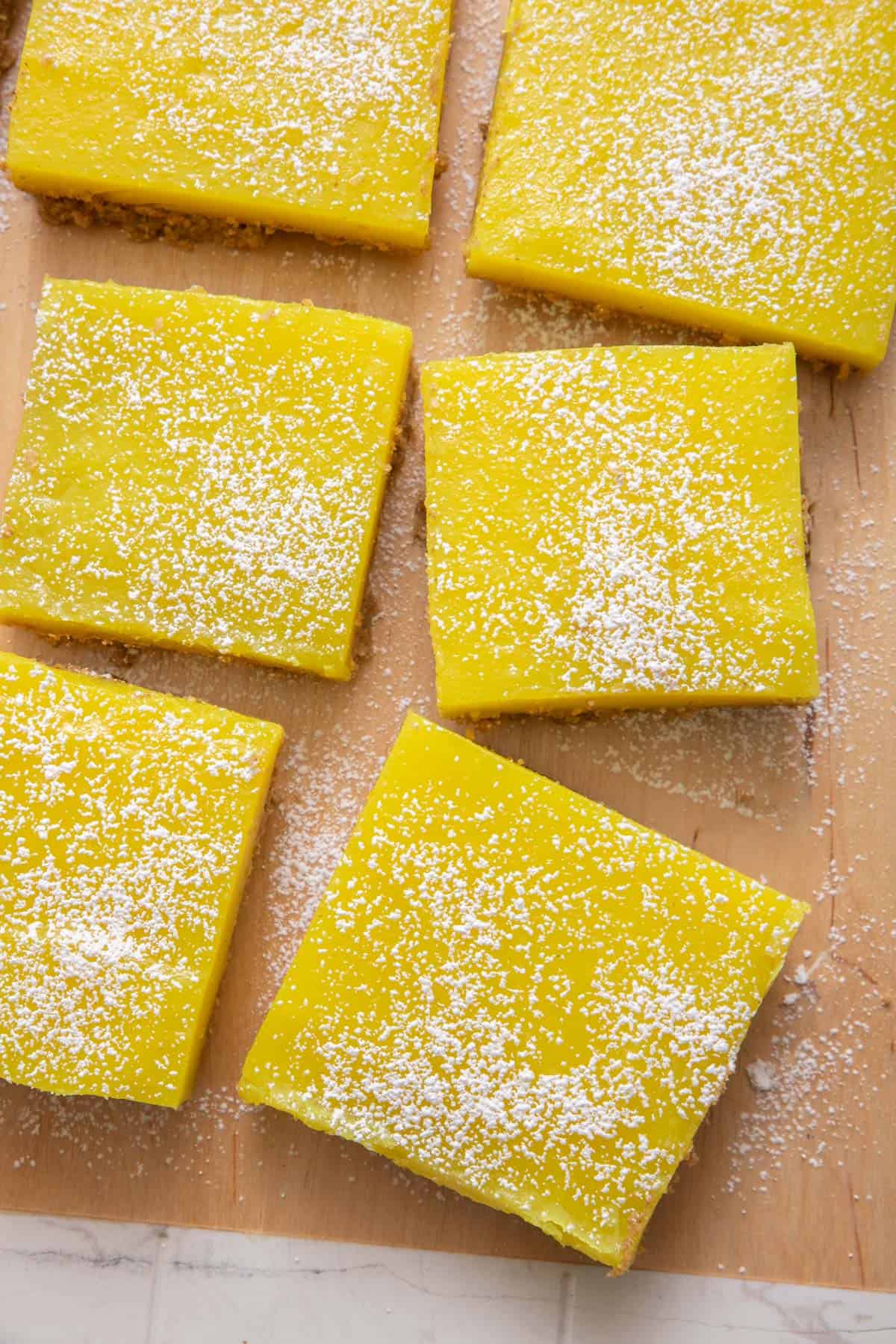 Sliced vegan lemon bars dusted with powdered sugar on cutting board