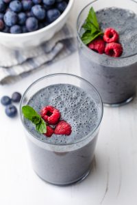 Blueberry banana smoothie topped with raspberries and mint