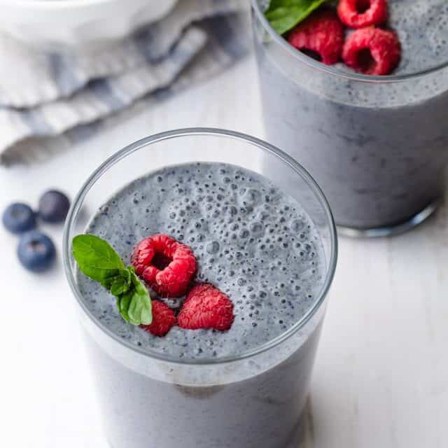 Blueberry banana smoothie topped with raspberries and mint