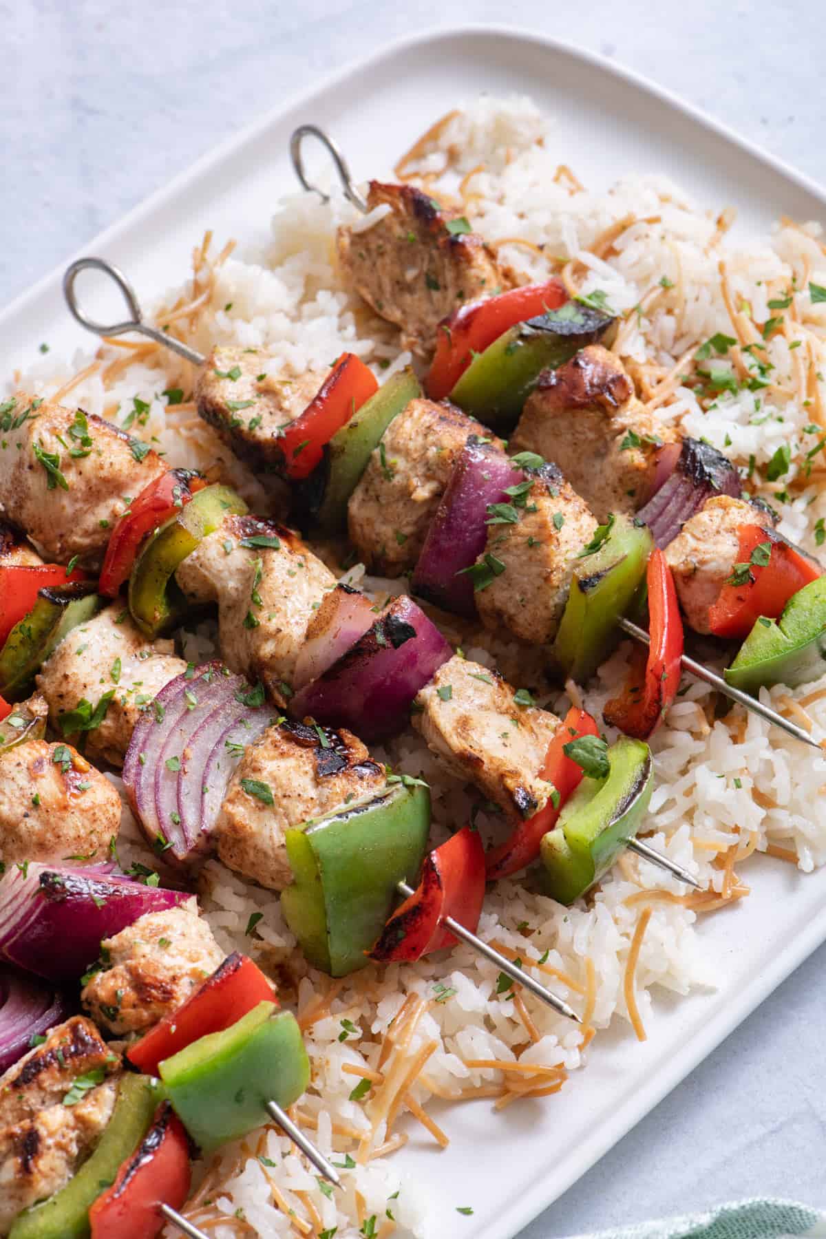 Cooked chicken kabobs on platter with Lebanese rice