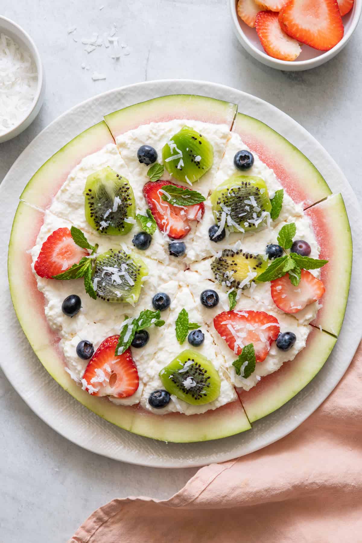 Watermelon pizza on large white plate cut into 8 pieces.