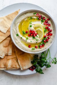 Lebanese baba ganoush in a bowl garnished with olive oil, parsley and pomegranate served with arabic bread (pita)