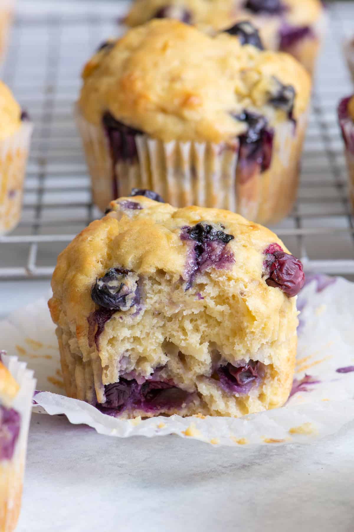Close up of banana blueberry muffin with a bit taken out and more muffins around it.