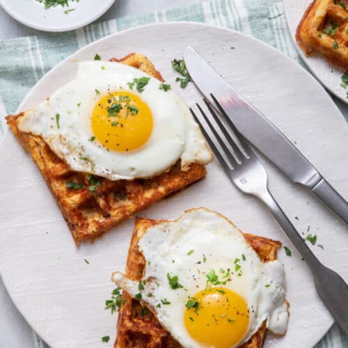 Final plated cauliflower waffles with eggs on top and parsley