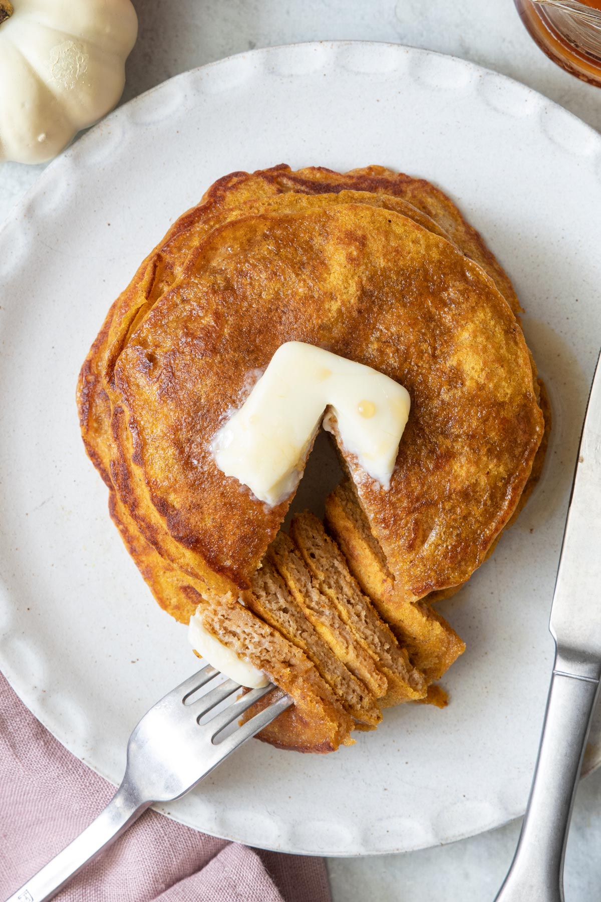 Stack of pumpkin pancakes cut out with fork on plate.