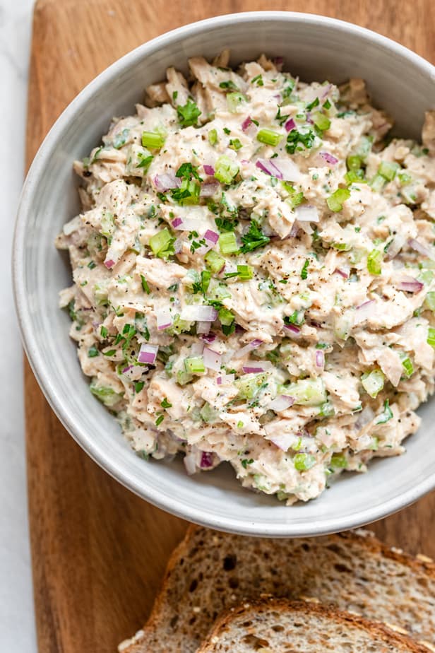 Final tuna salad in a large bowl with bread slices nearby
