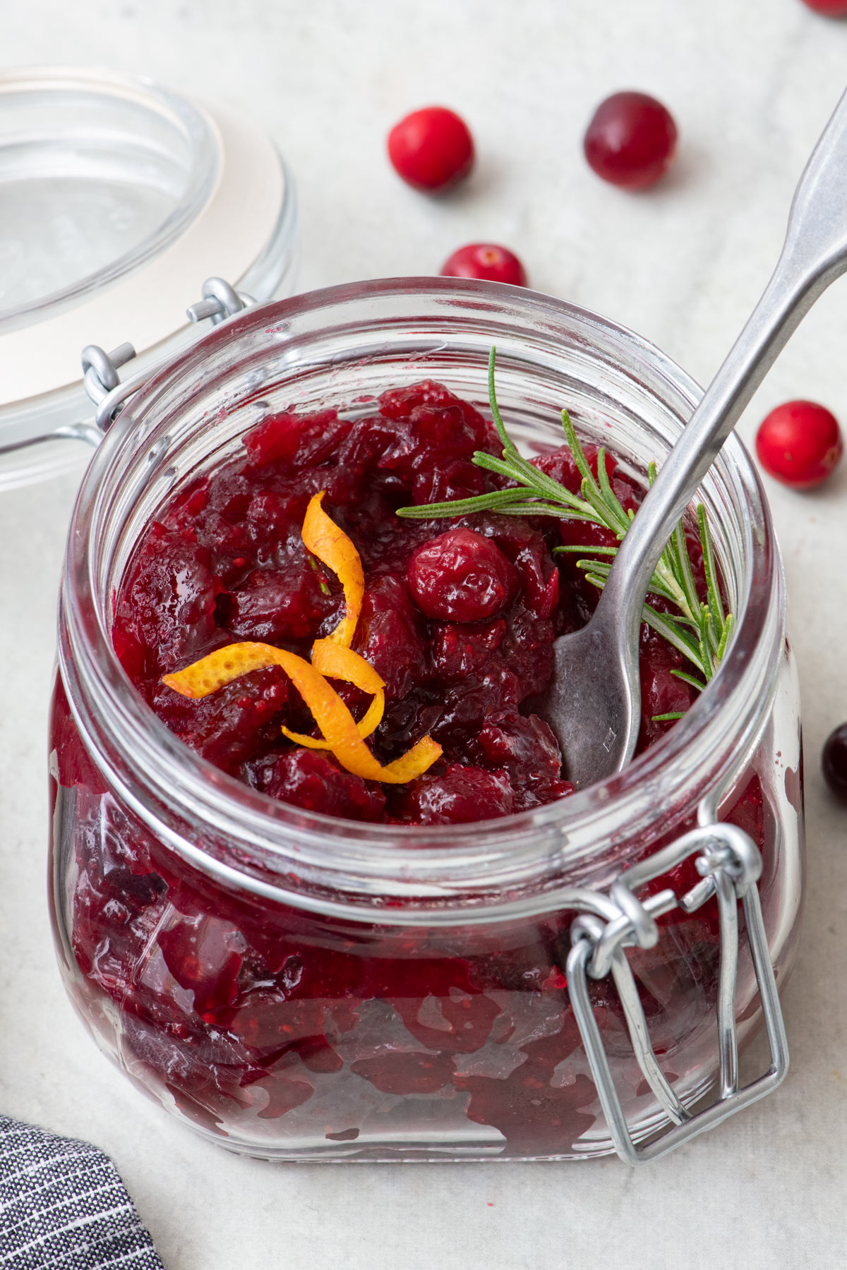 Close-up shot of the cranberry orange sauce with a spoon in the jar for scooping.