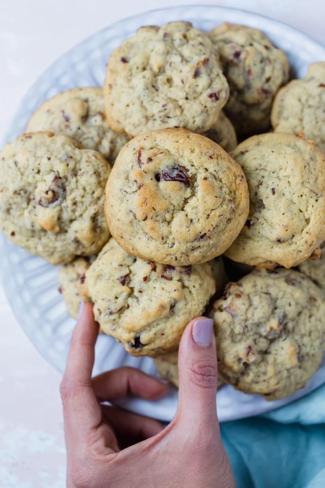 Plate of date cookies with one hand going in to grab a cookie