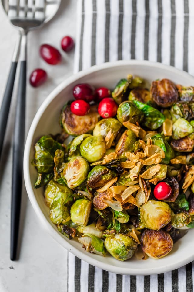 Final plating of pan roasted brussel sprouts topped with garlic and garnished with cranberries