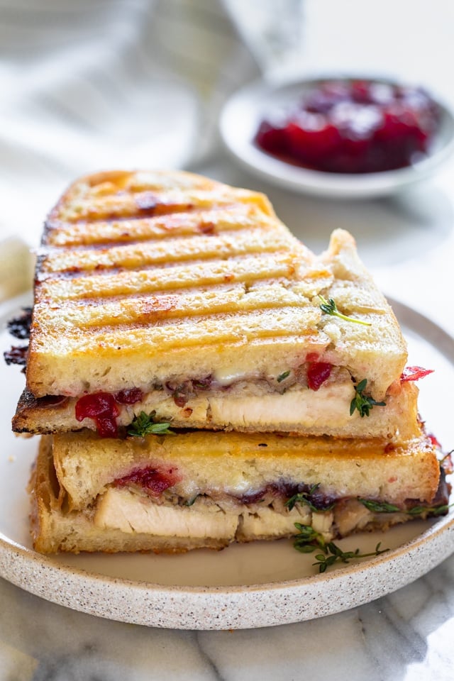 Stack of two halves of turkey panini straight from the grill with a side of cranberry sauce