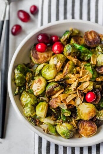 Final plating of pan roasted brussel sprouts topped with garlic and garnished with cranberries