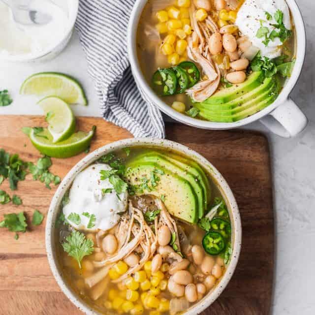 Final easy white chicken chili served in two bowls with toppings