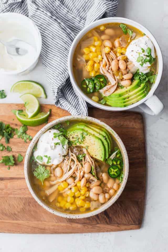 Final easy white chicken chili served in two bowls with toppings