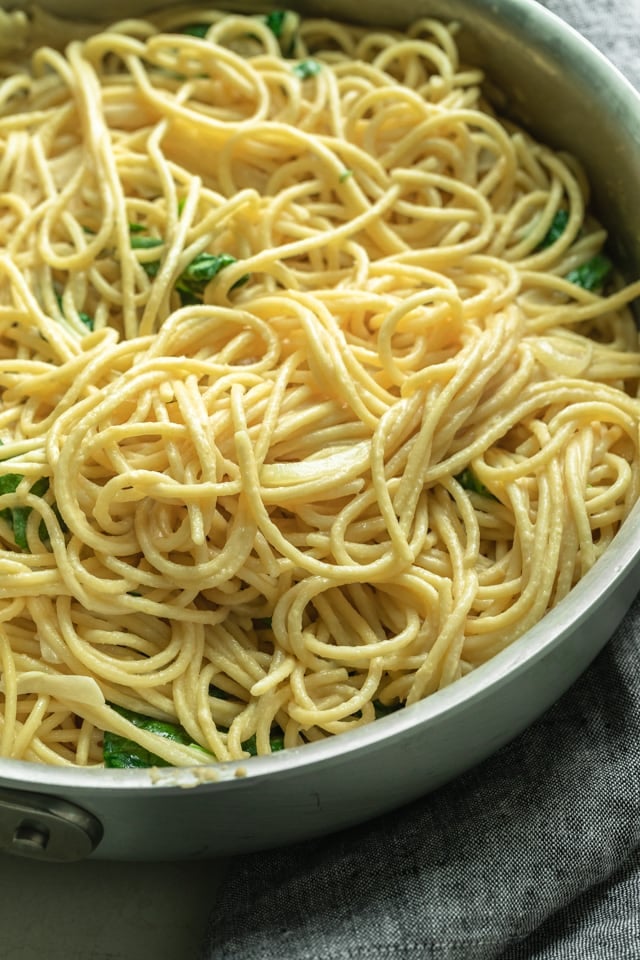 Cooked spaghetti added to the onions, garlic, spinach and hummus mixture